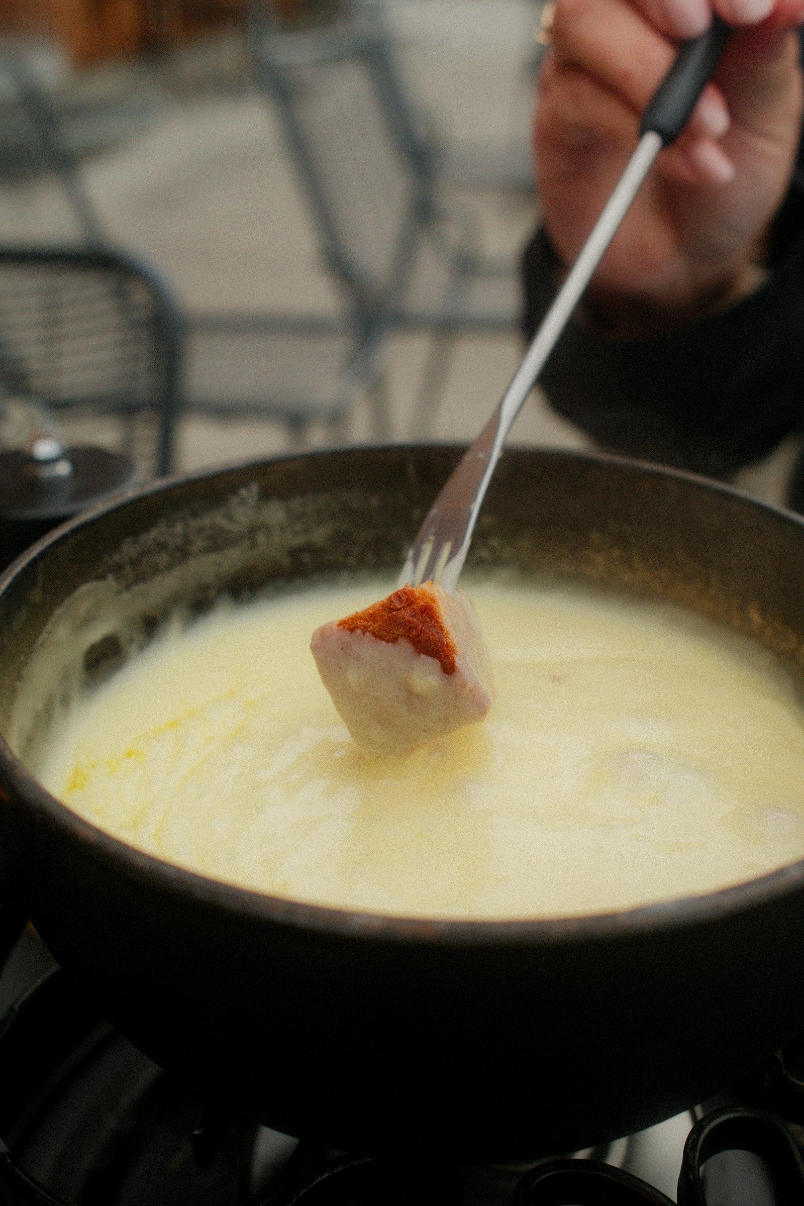 Brot wird in ein Käsefondue getaucht